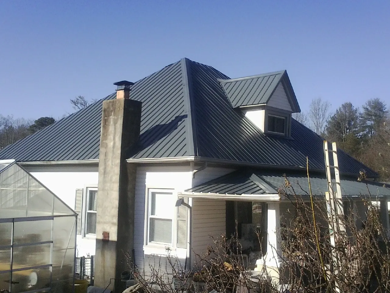 Dark blue standing seam metal roof on a white farmhouse with dormer — Slate & Tile Roof Repair by Roofing Brothers in South River