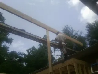 Carpenter setting a ridge beam over a new addition frame — Ice Dam Removal by Roofing Brothers in South River