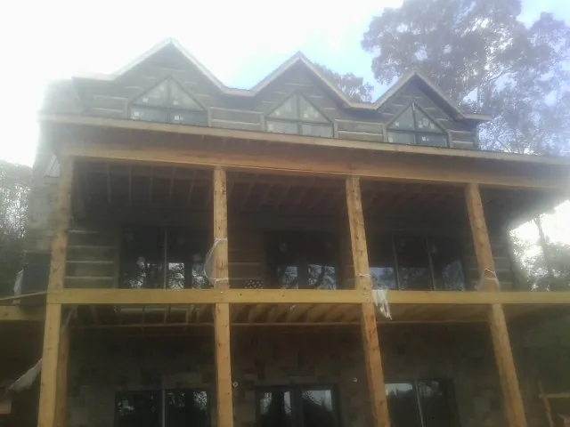 Dormers and porch framing on a large log home under construction — Roof Coating work by our crew in South River
