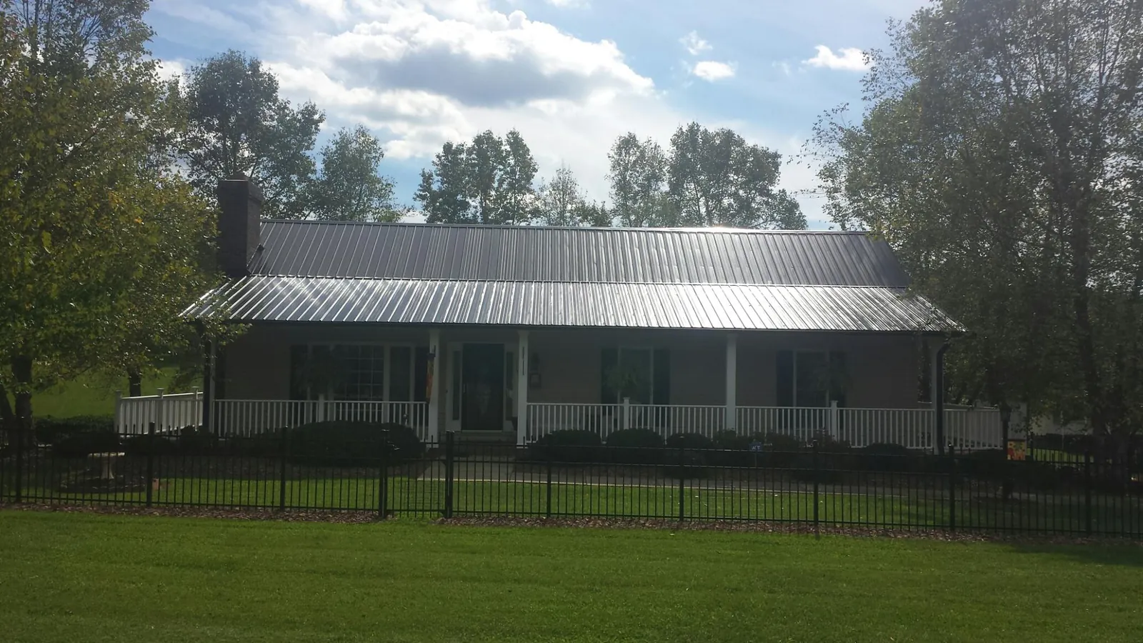 Gray metal roof on a brick ranch with a full width front porch — Gutter Guard Installation work by our crew in South River