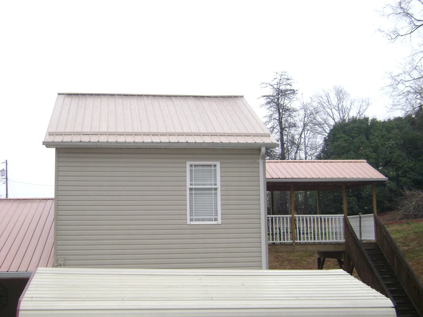 Tan metal roofs on a two story addition and attached porch, from a Roof Replacement job in South River