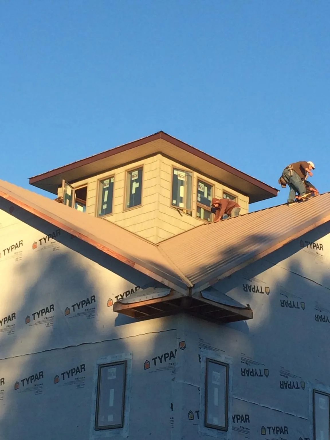 Roofers working around a rooftop cupola on a new metal roof at sunset — Roof Waterproofing in South River by Roofing Brothers